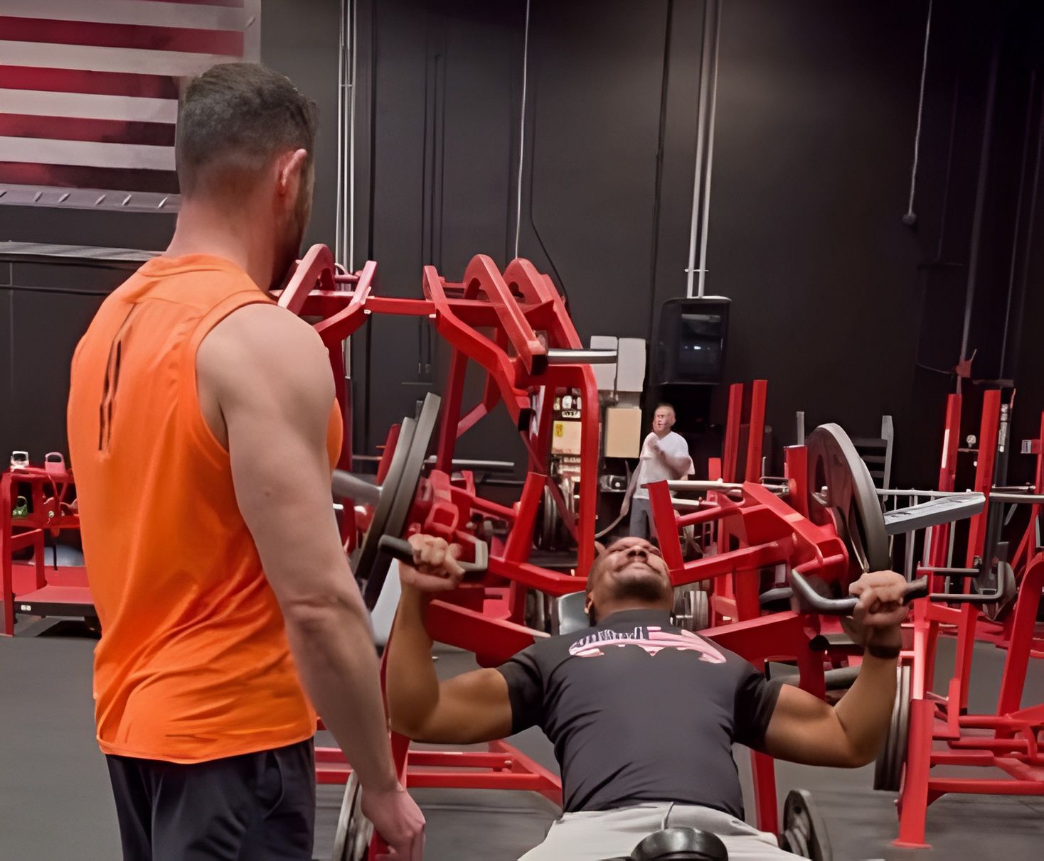 Coach Chris spotting a client through a set on a plate-loaded chest press