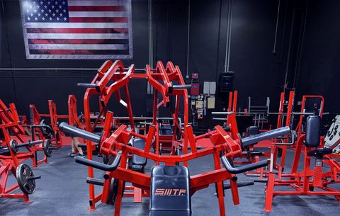 The gym floor at Santa Margarita Training Facility, rows of red plate-loaded machines under a US flag