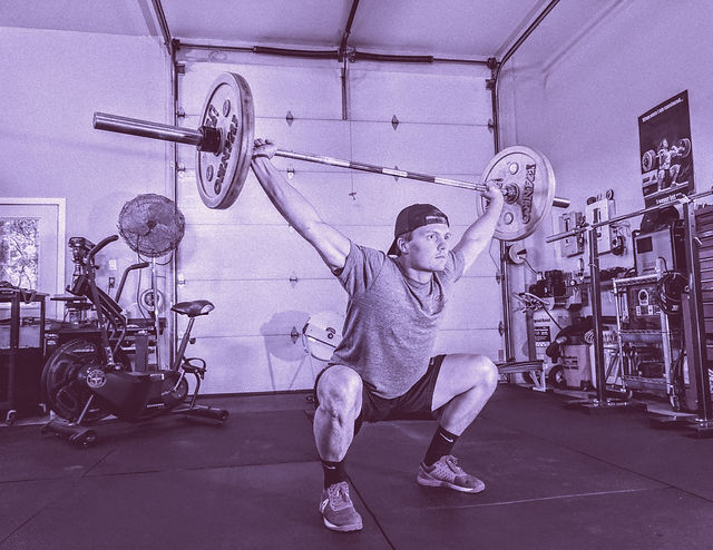 A lifter at the bottom of an overhead squat, barbell locked out overhead